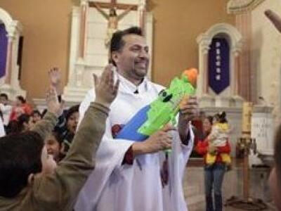 Ιερέας ρίχνει αγιασμό στους πιστούς με ν...